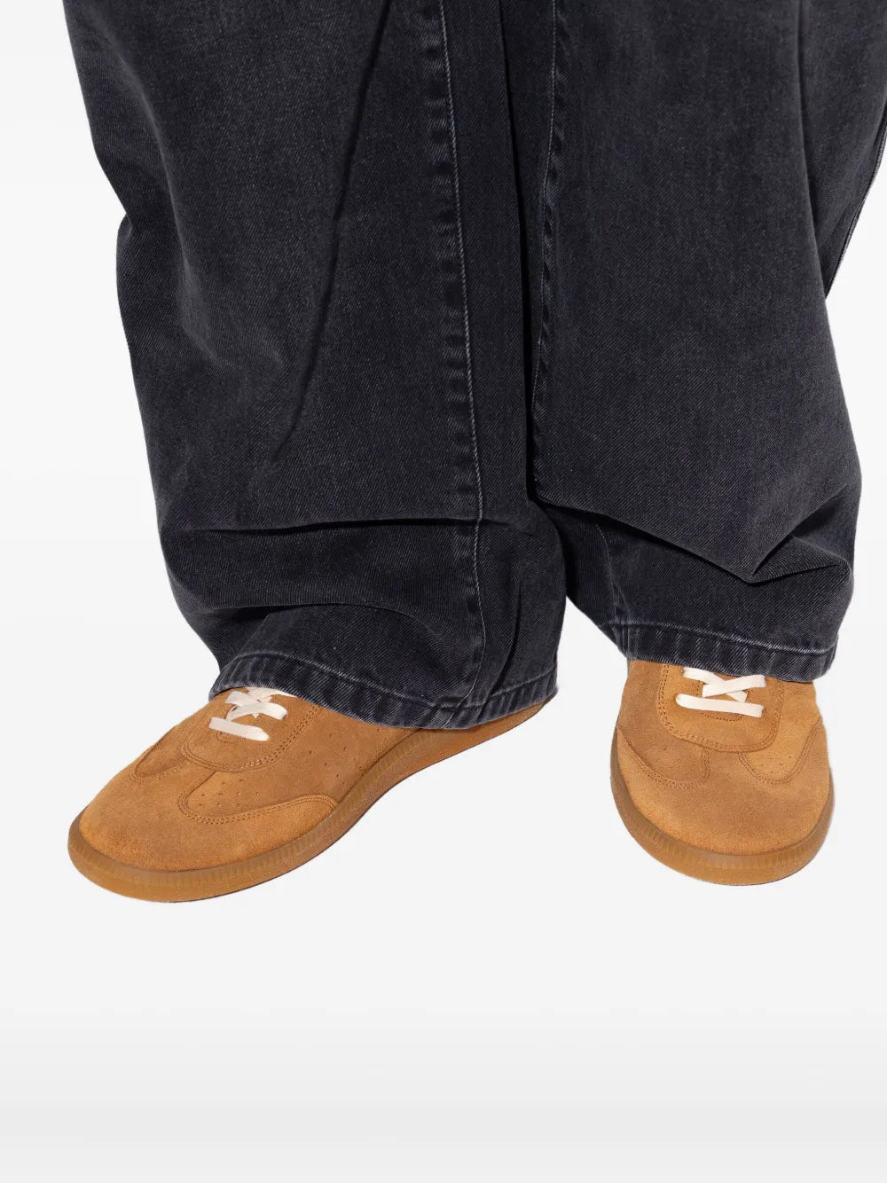 Brown suede sneakers worn with jeans; white laces and low-profile sole