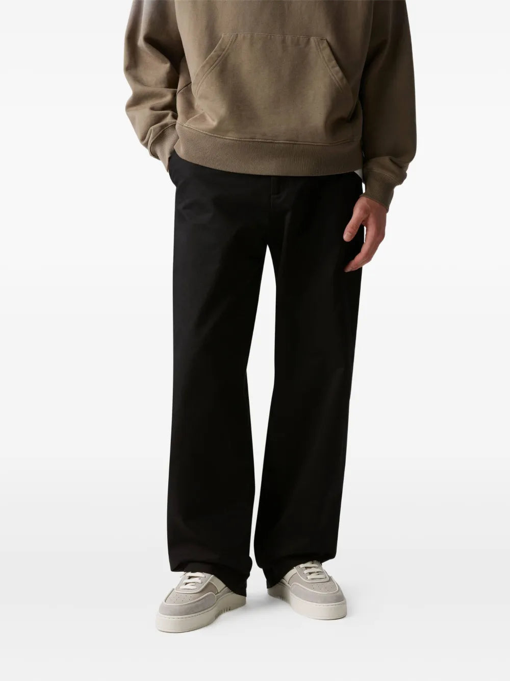 Light taupe sneakers worn with dark trousers, lace-up style and low rubber sole