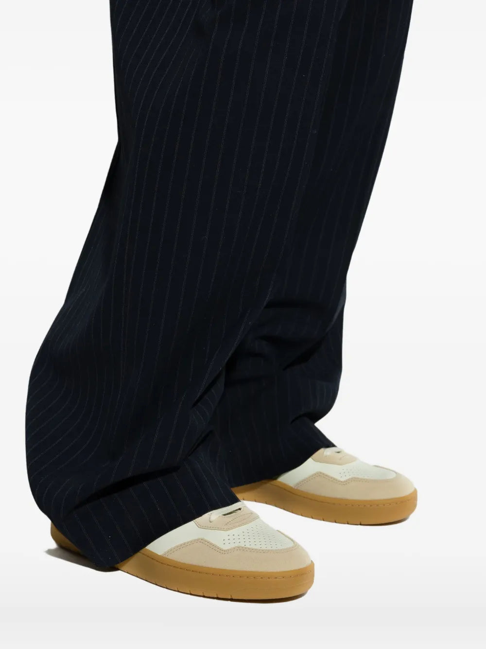 Sneakers with green V logo and gum sole worn with dark pinstripe trousers