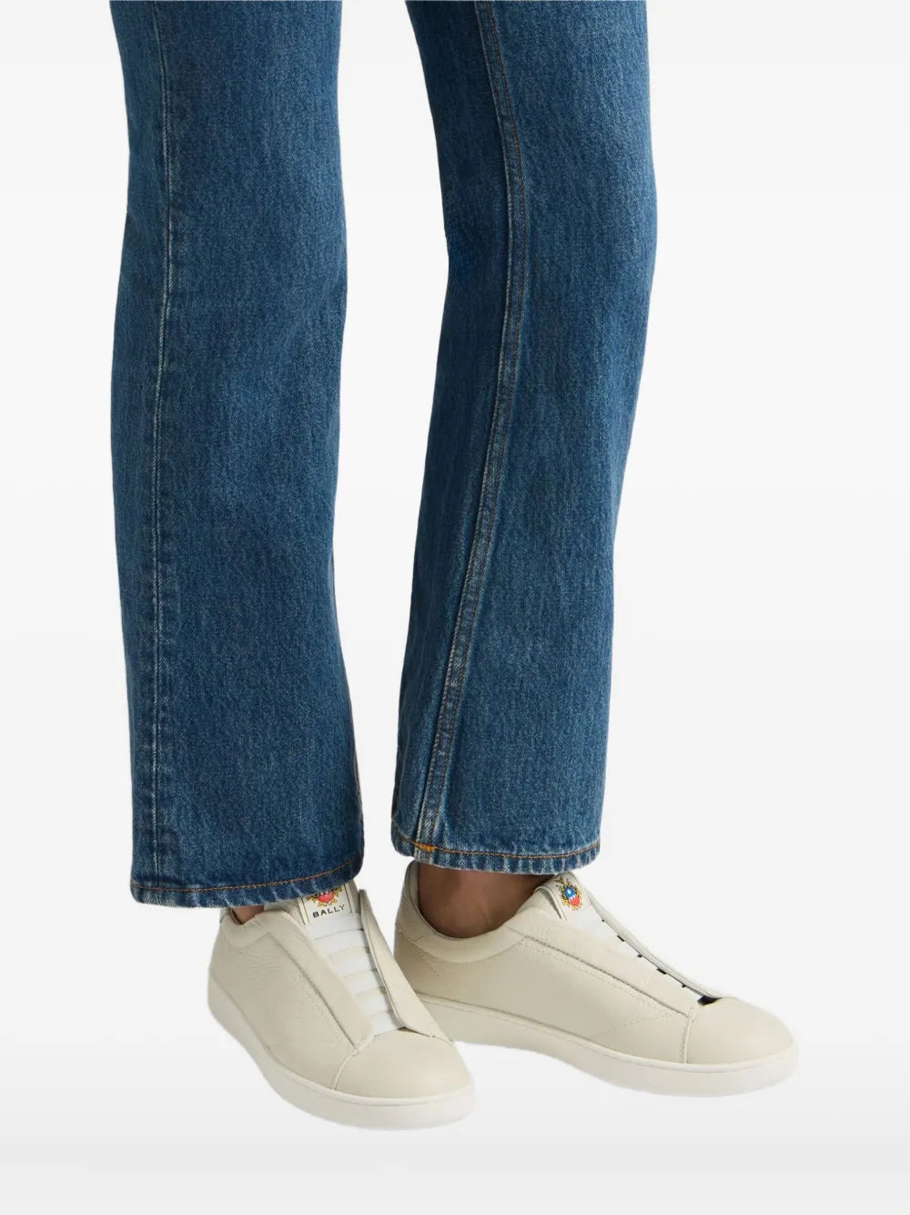 Beige leather low-top sneakers worn with blue jeans and white rubber soles
