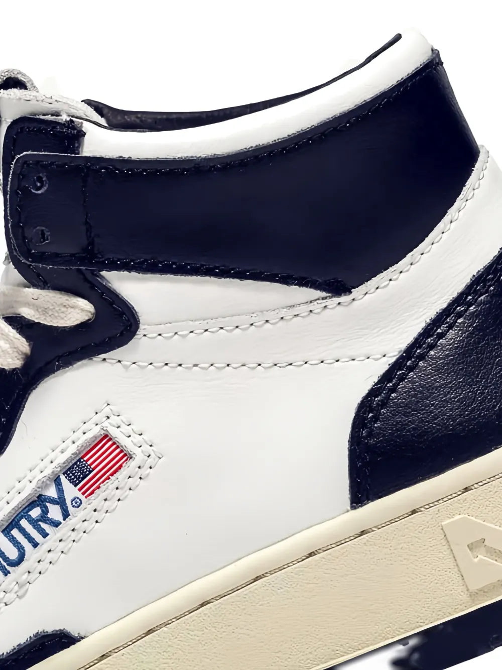 White and navy leather high-top sneaker close-up with flag patch and stitched trim