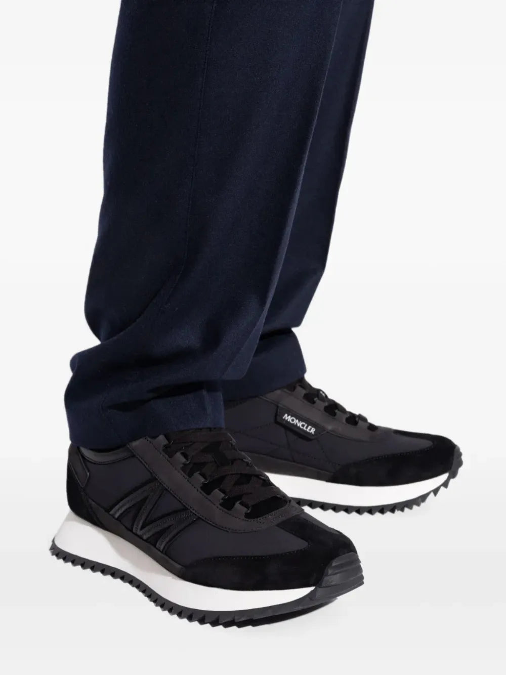 Black Moncler panelled sneakers with dark trousers and lace-up design
