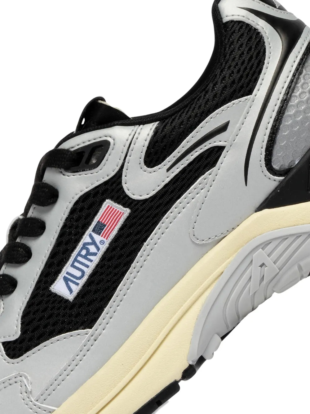 Autry lace-up sneaker close-up with black laces, grey upper, and textured side panel
