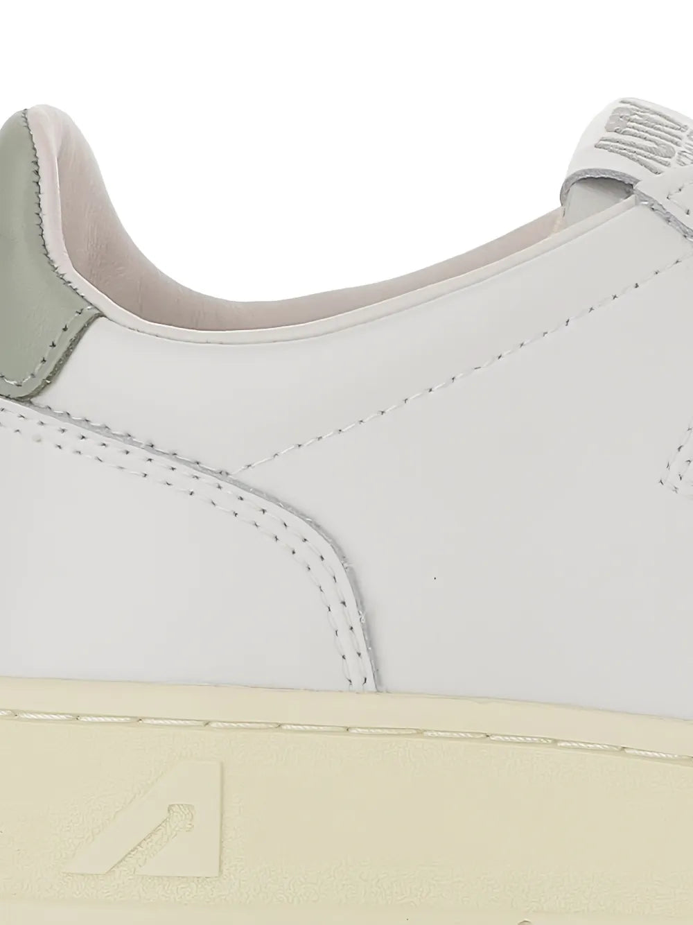 White sneaker upper close-up with perforated panels and lace eyelets