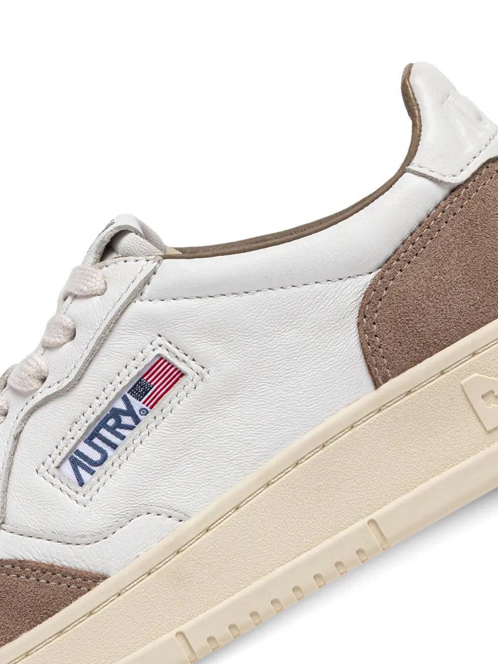 Close-up of white and brown suede-panel sneaker with lace and logo patch