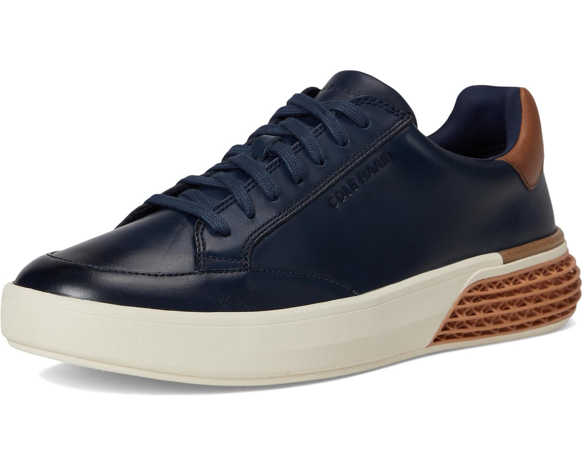 Navy lace-up low-top sneakers with tan heel tab and brown textured midsole, cream sole.