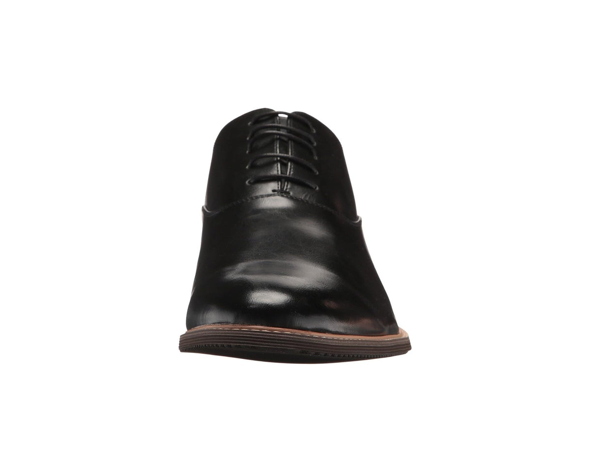 Black lace-up dress shoe front view with glossy finish and brown trim