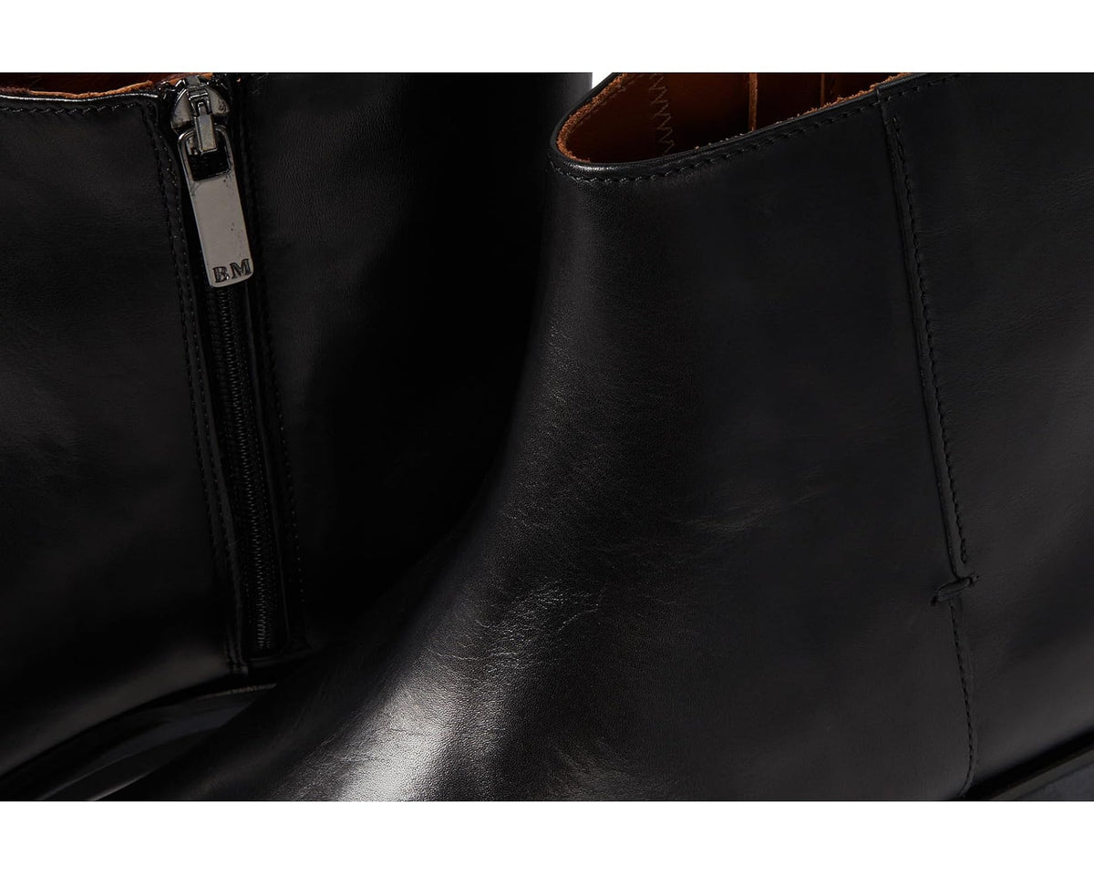 Black leather ankle boot close-up with side zipper and stitched panel