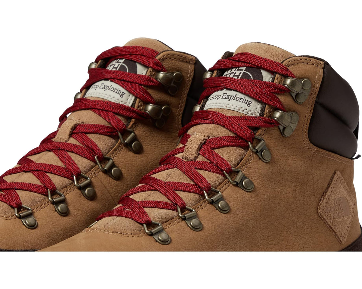Close-up of tan hiking boots with red laces, metal eyelets, and dark ankle panel