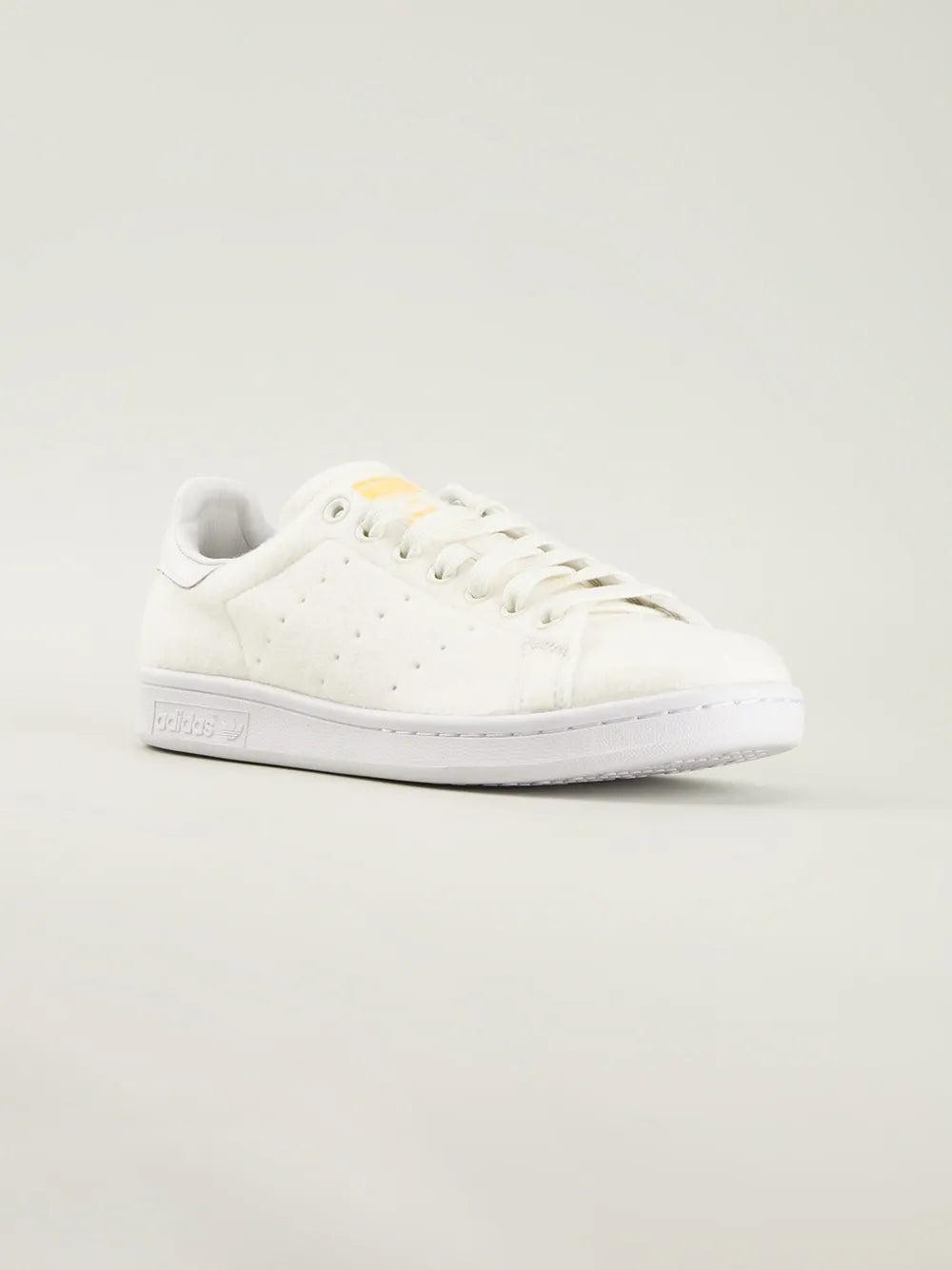 White low-top Adidas sneakers with perforated toe and lace-up closure