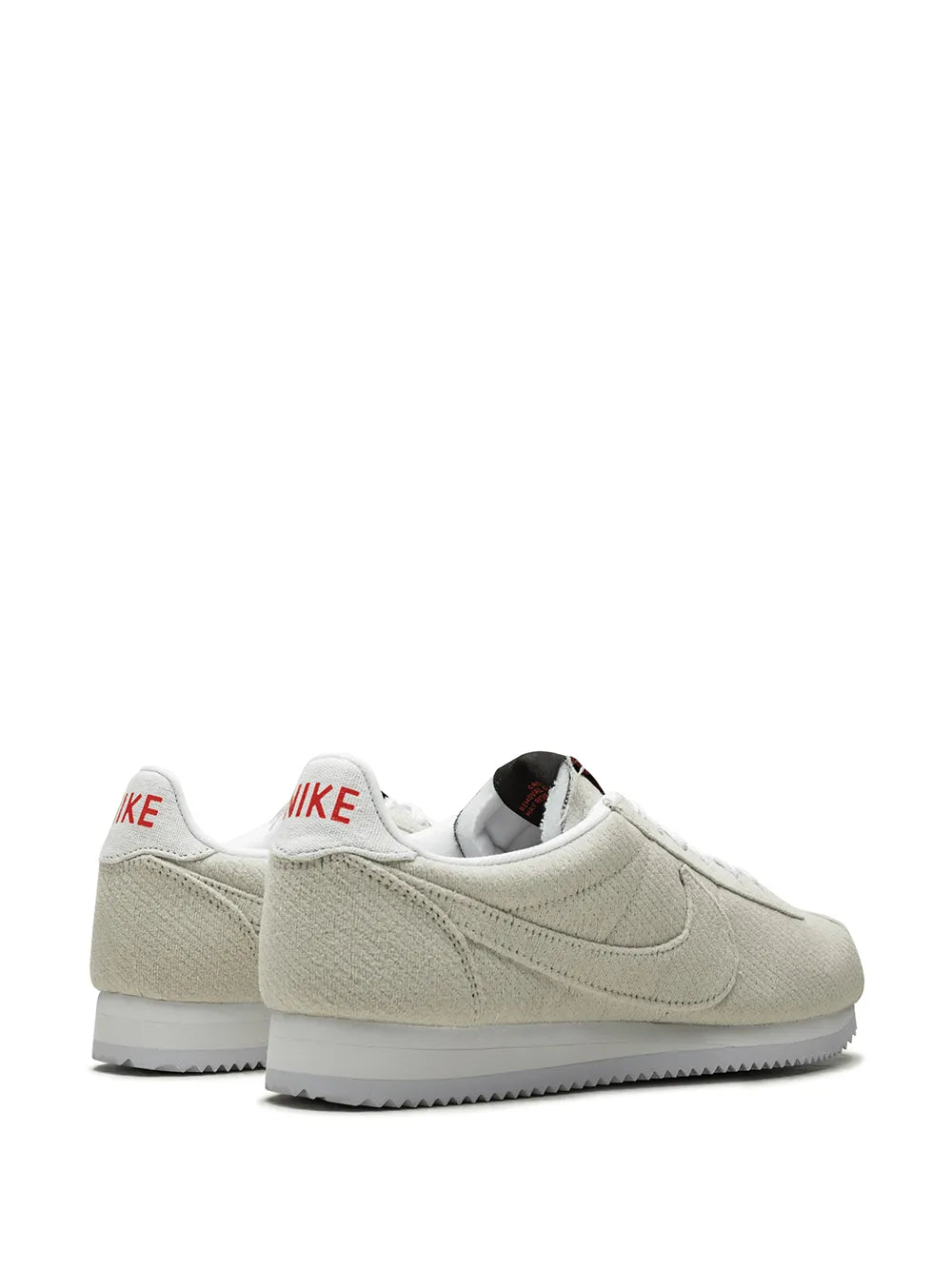Pair of tan Nike Cortez QS sneakers showing swoosh and heel collar