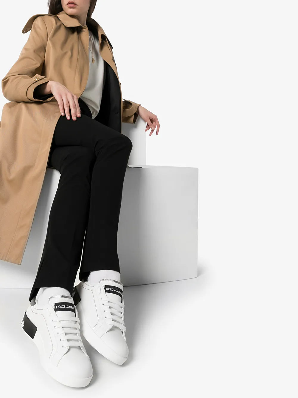 White leather low-top sneakers on model with black logo heel tab