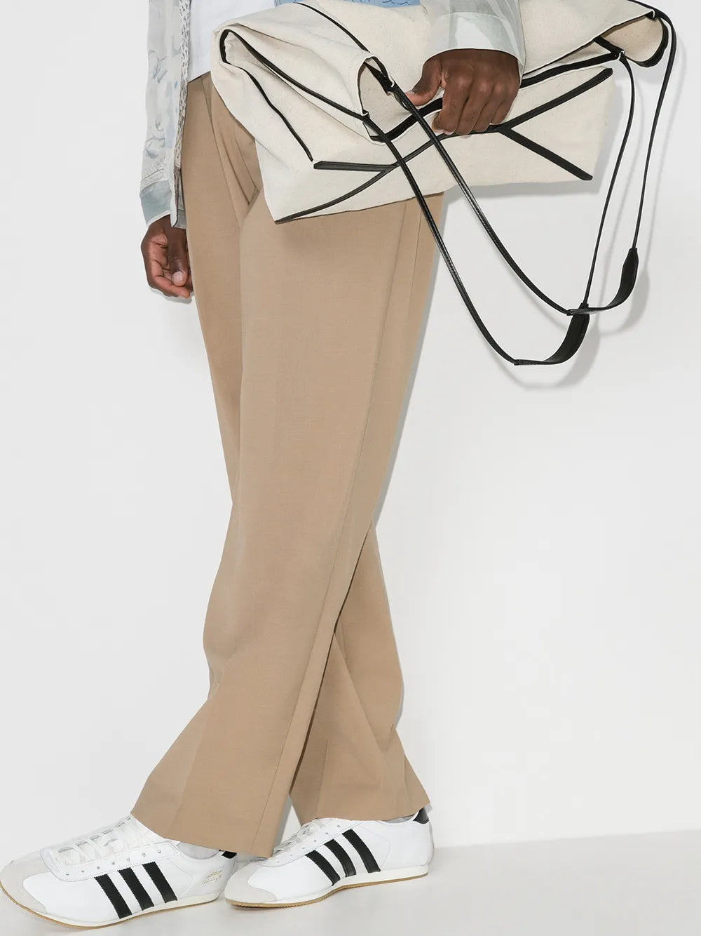 White and black leather sneakers worn with tan flared pants