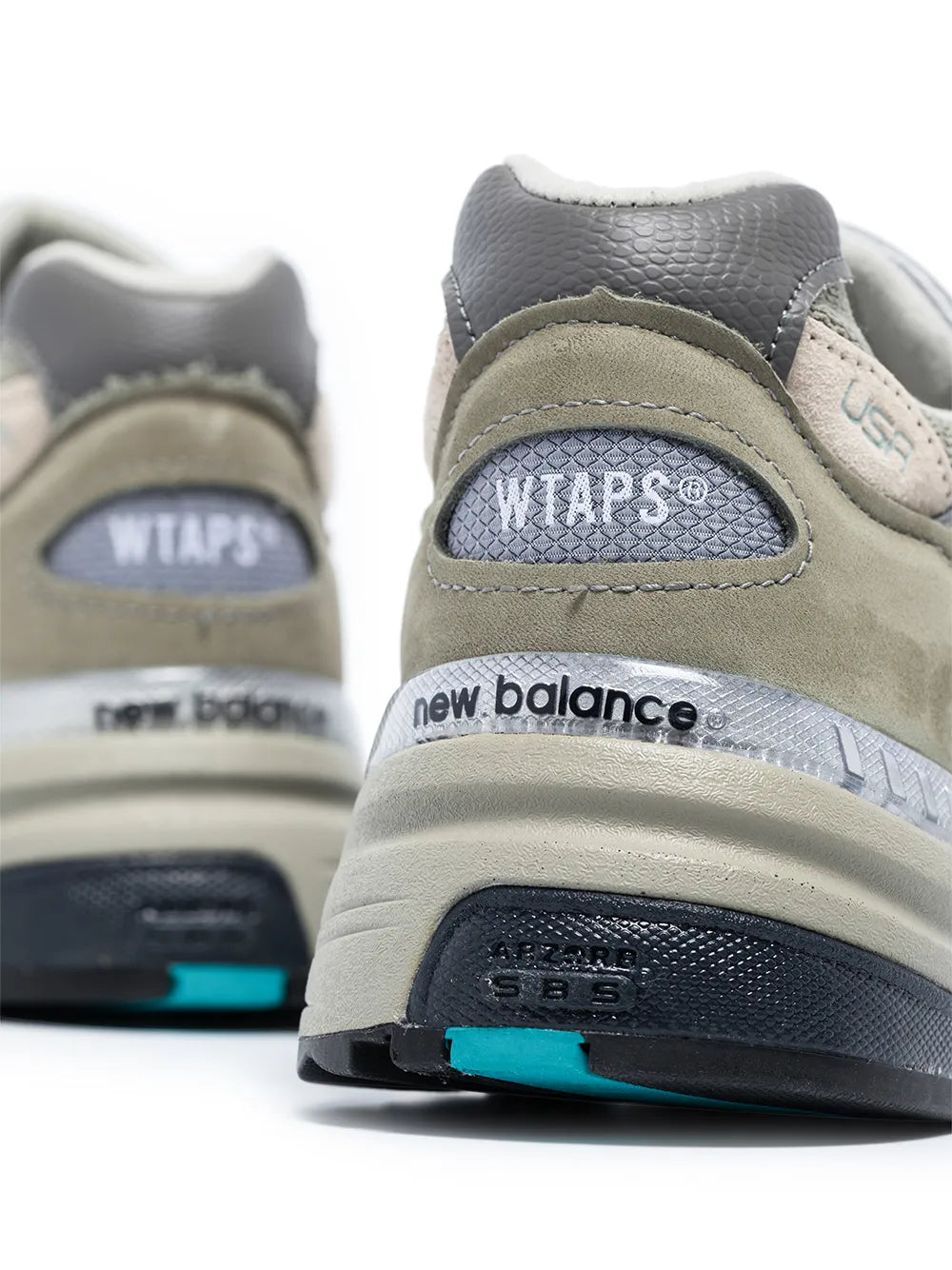 New Balance sneaker heel close-up with WTAPS patch and teal midsole detail