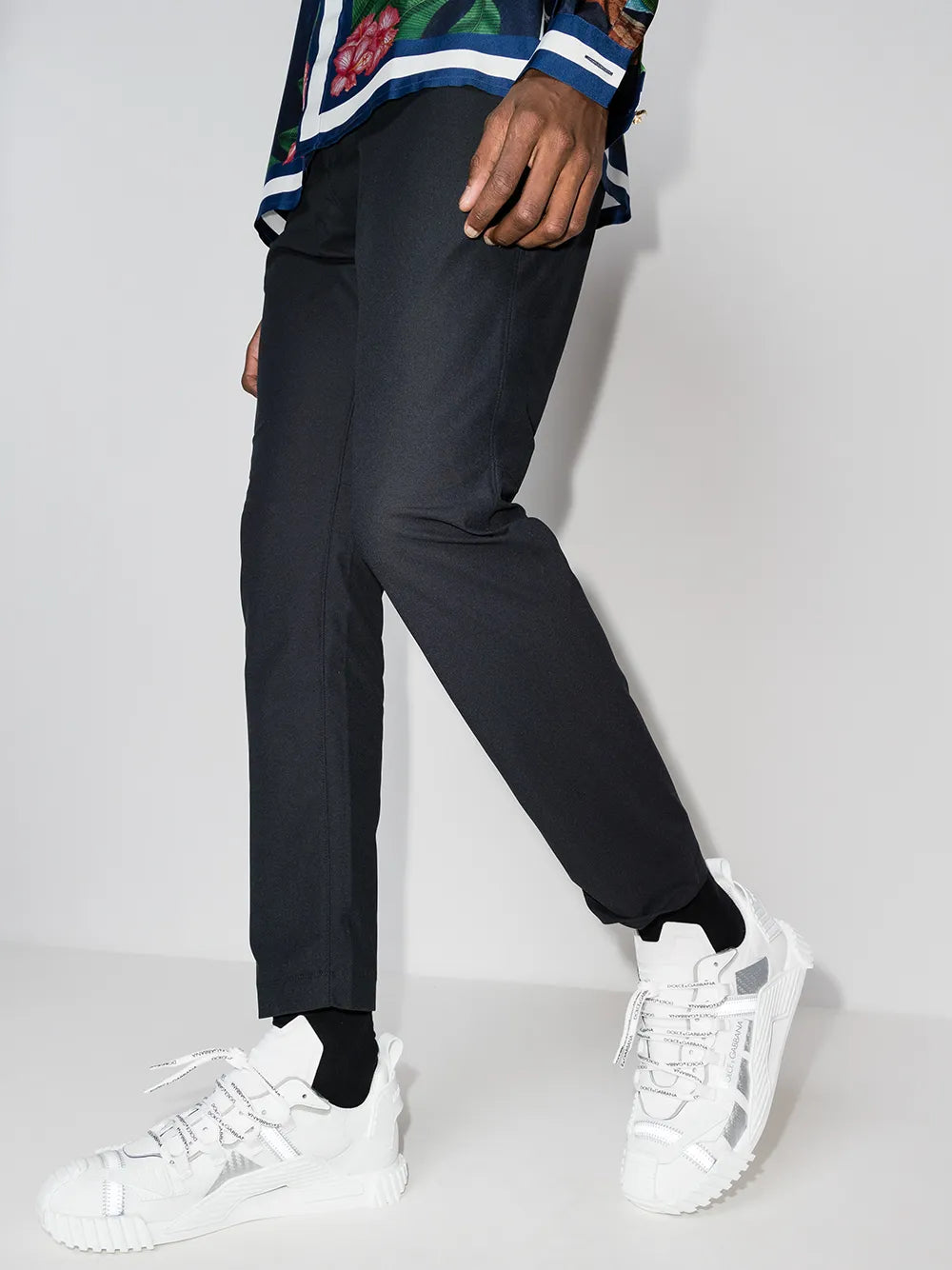 White low-top sneakers worn with dark pants, lace-up and chunky sole