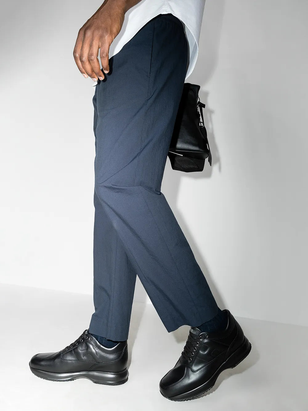 Black lace-up low-top sneakers worn with dark trousers