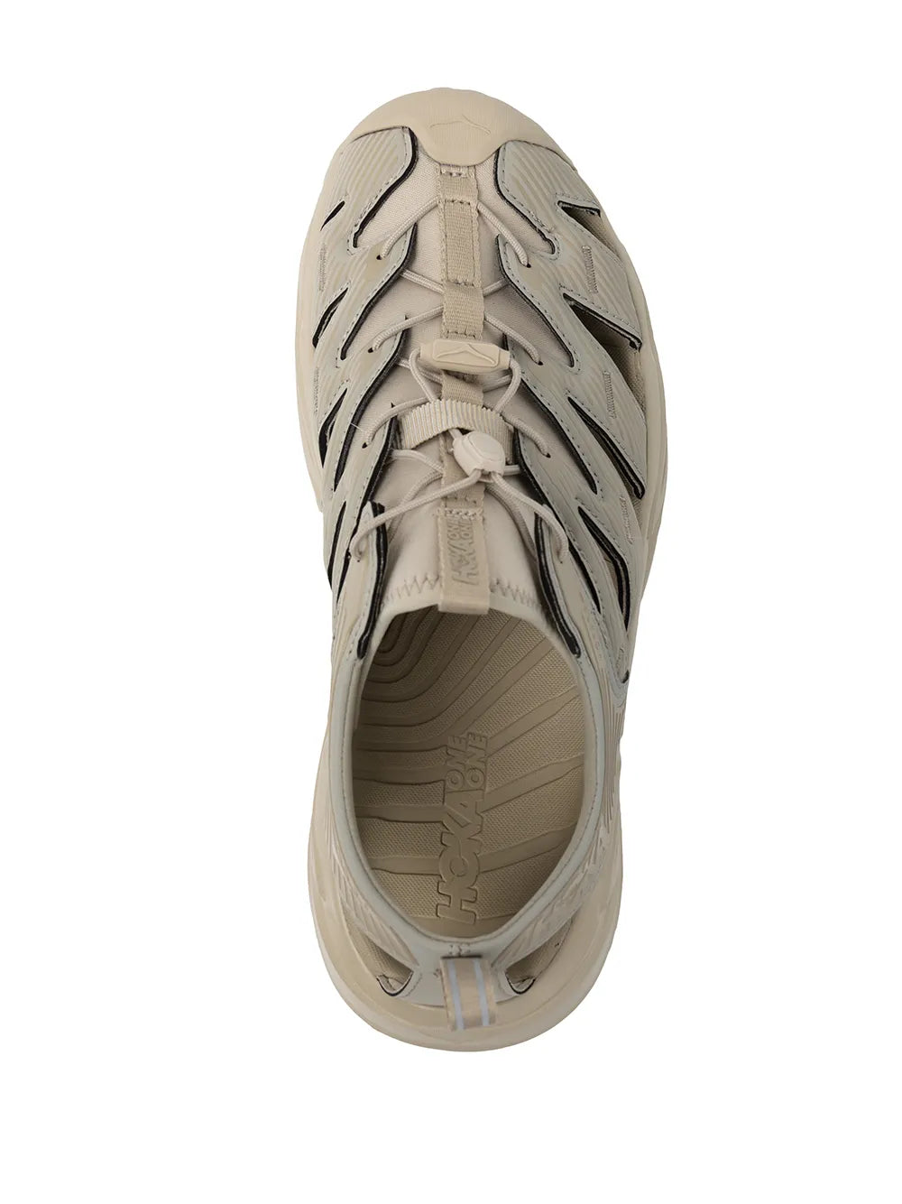 Beige low-top sneaker with lace closure, black stitching details, and treaded sole