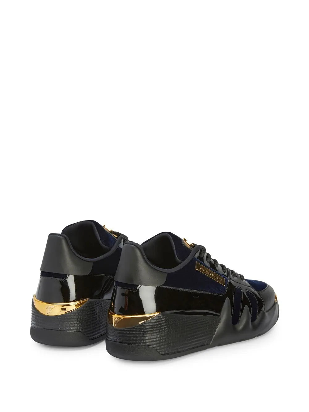Black low-top sneakers with metallic gold heel accents and perforated toe detail
