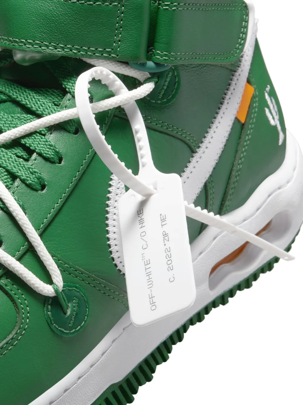 Green sneaker close-up with white laces, Off-White tag, and white side panel detail.