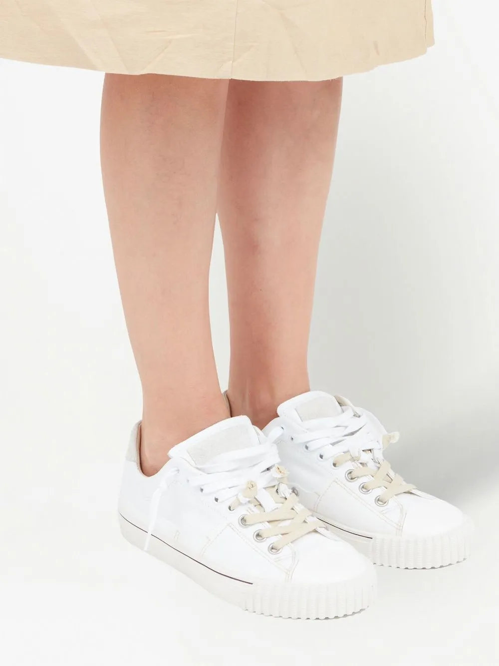 Maison Margiela off-white low-top sneakers on feet, lace-up front visible
