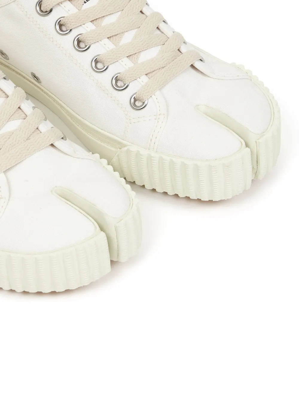 Close-up of white Tabi low-top sneaker toe and side stitching with lace eyelets.