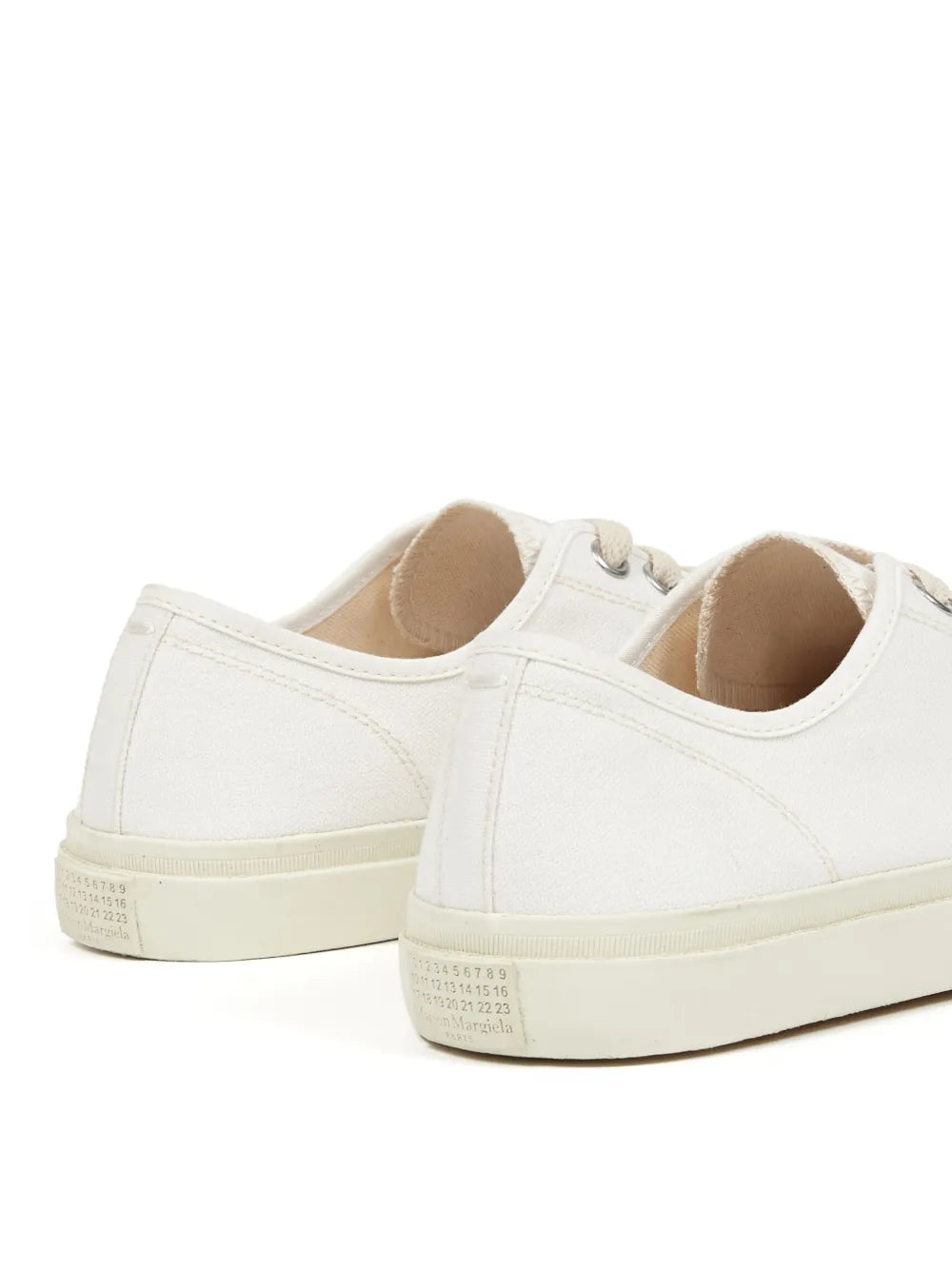 Side view of white Tabi low-top sneakers with seam detailing and flat rubber sole.