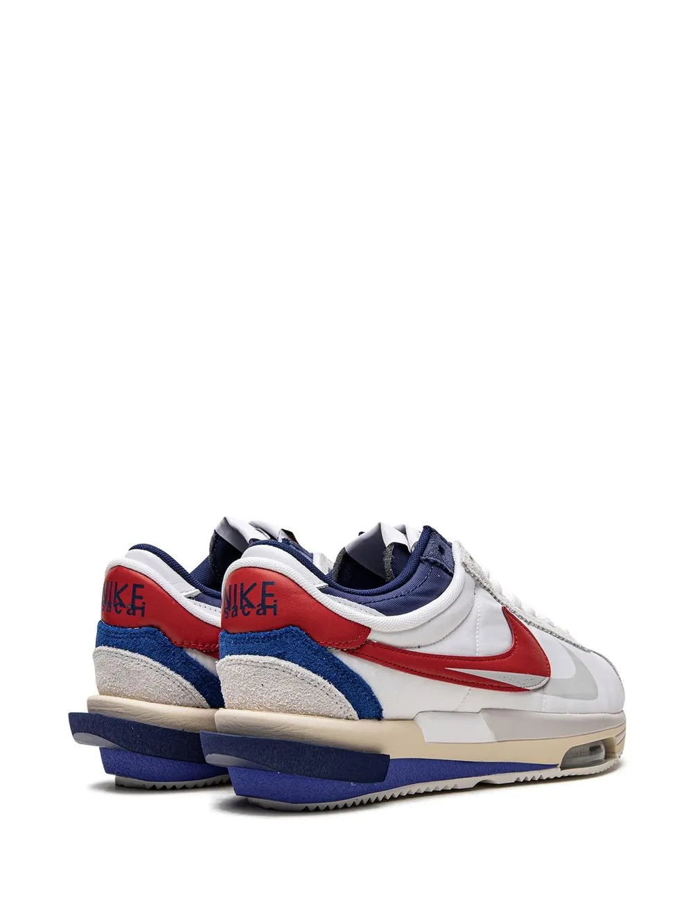 Pair of white sneakers with red swoosh, blue heel tabs, navy lining, Nike x Sacai Cortez
