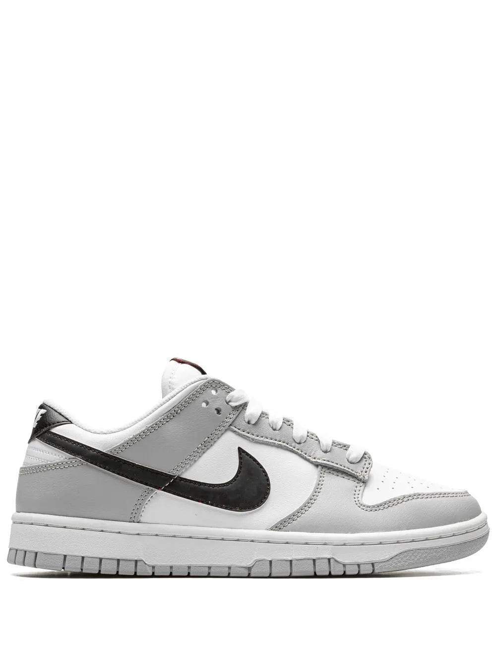Low-top sneaker with white leather upper, black Swoosh, gray paneling, lace-up.