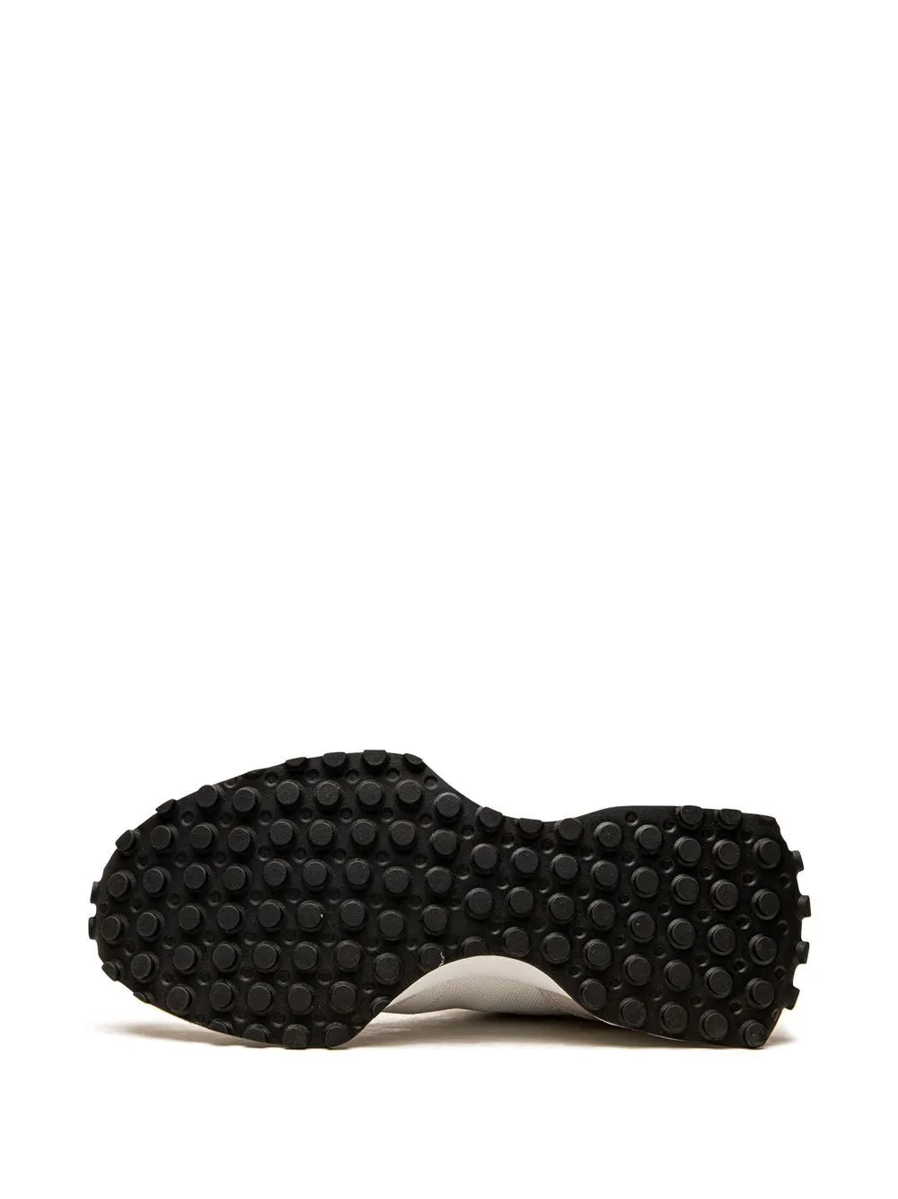 Black rubber outsole with circular traction nubs under cream sneaker
