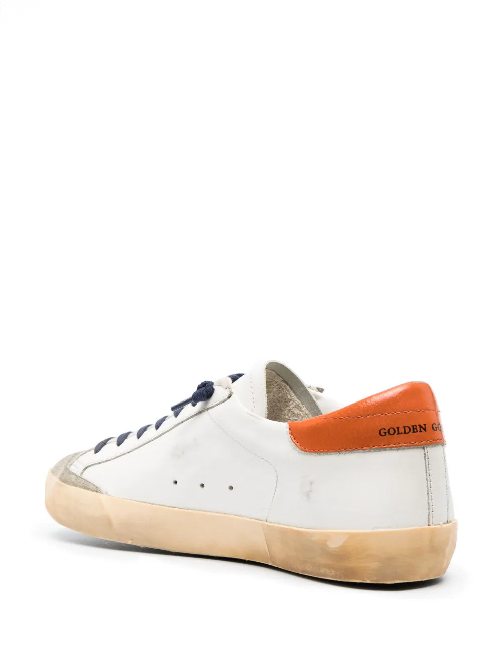 Off-white low-top sneakers with orange heel tab, navy laces, tan sole.