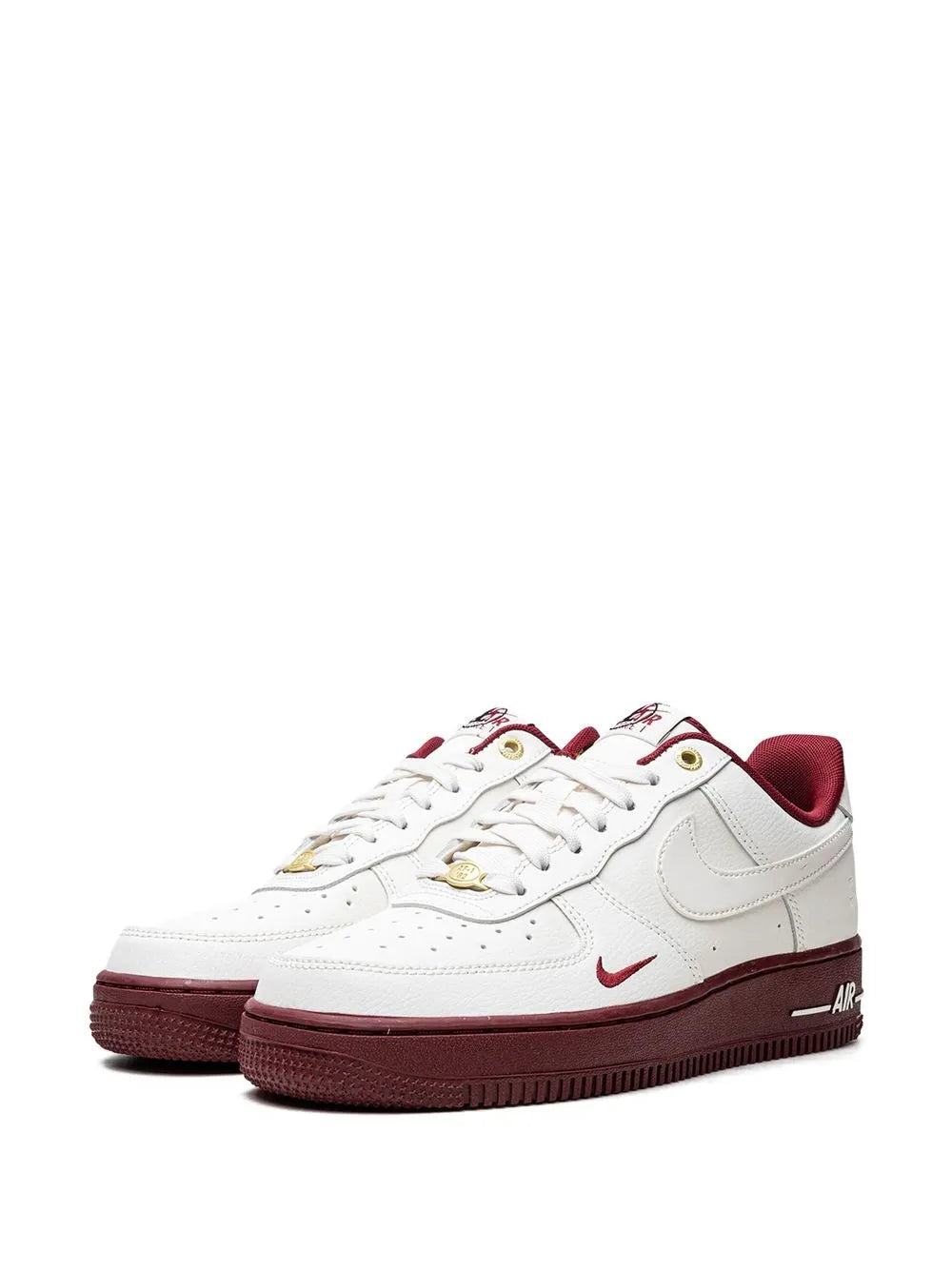 Pair of white Nike low-top sneakers with burgundy soles and gold lace eyelets