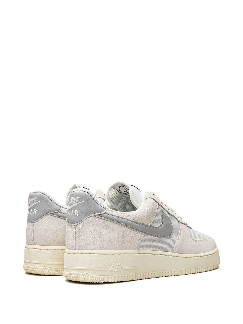Beige low-top sneakers with gray heel tabs, Nike swoosh, and lace-up design