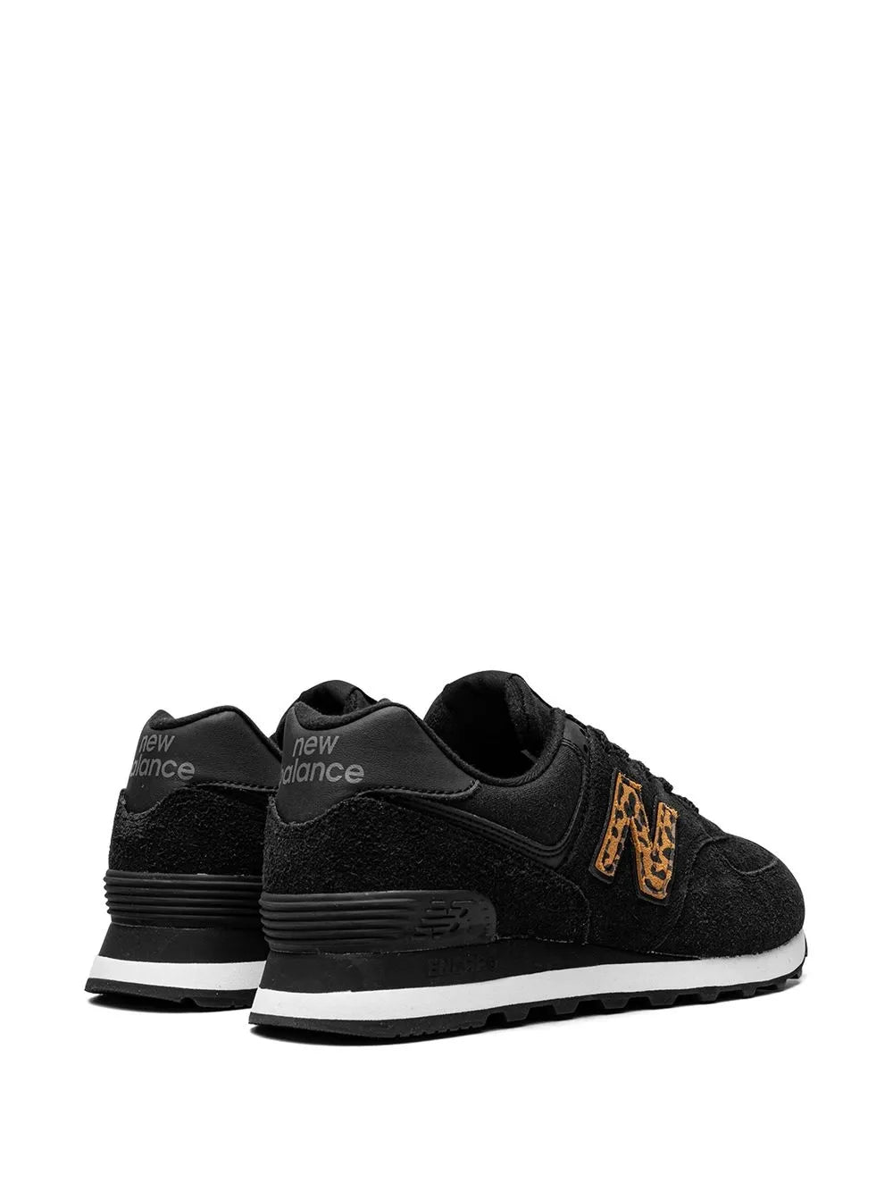 New Balance 574 sneaker pair in black, rear view with orange side logo