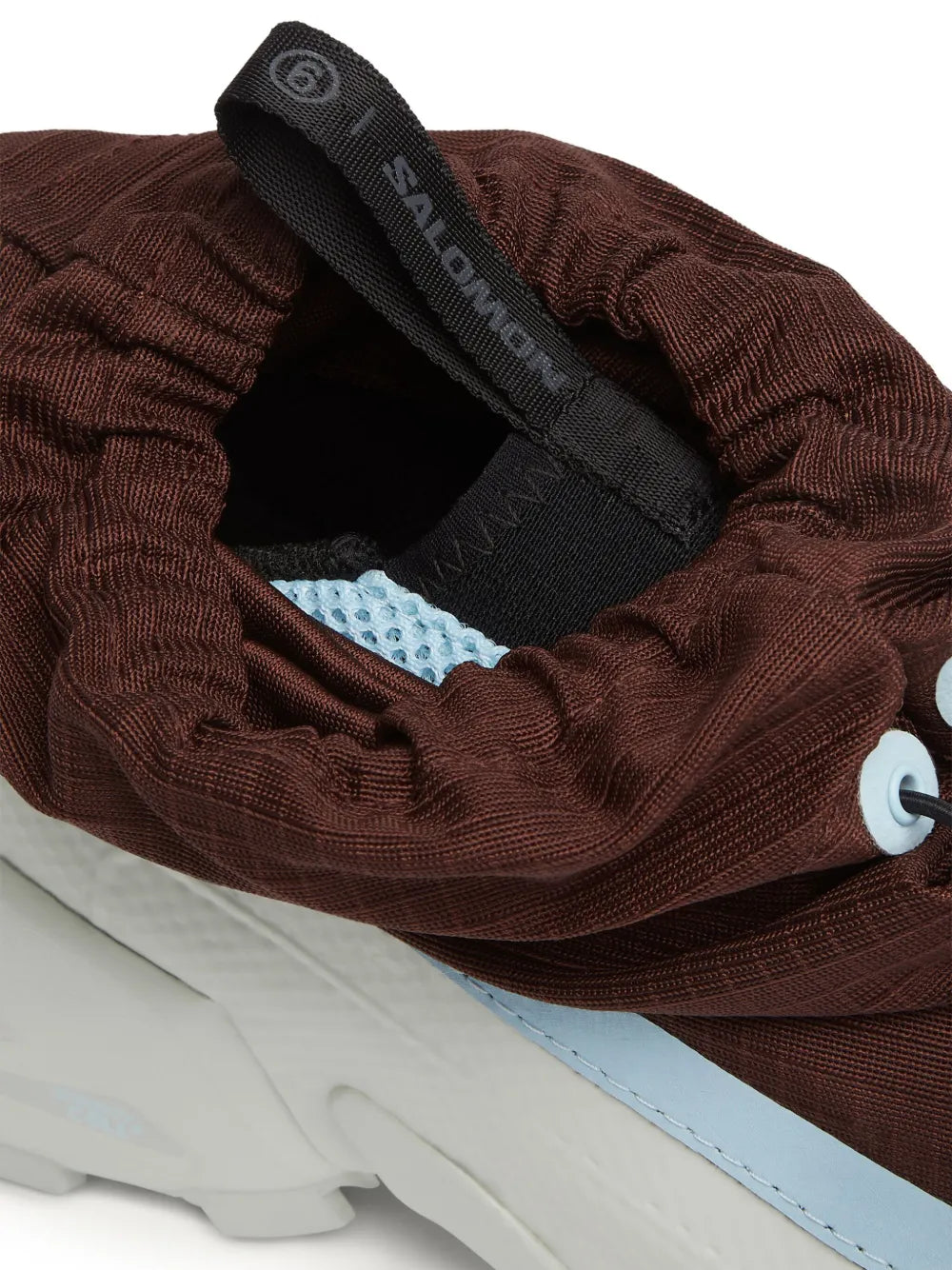 Brown mid-top sneaker with open tongue, black Salomon strap, light blue inner lining, white sole