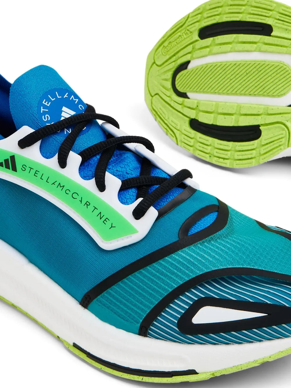 Close-up of blue adidas low-top sneaker upper with green logo and black lace details