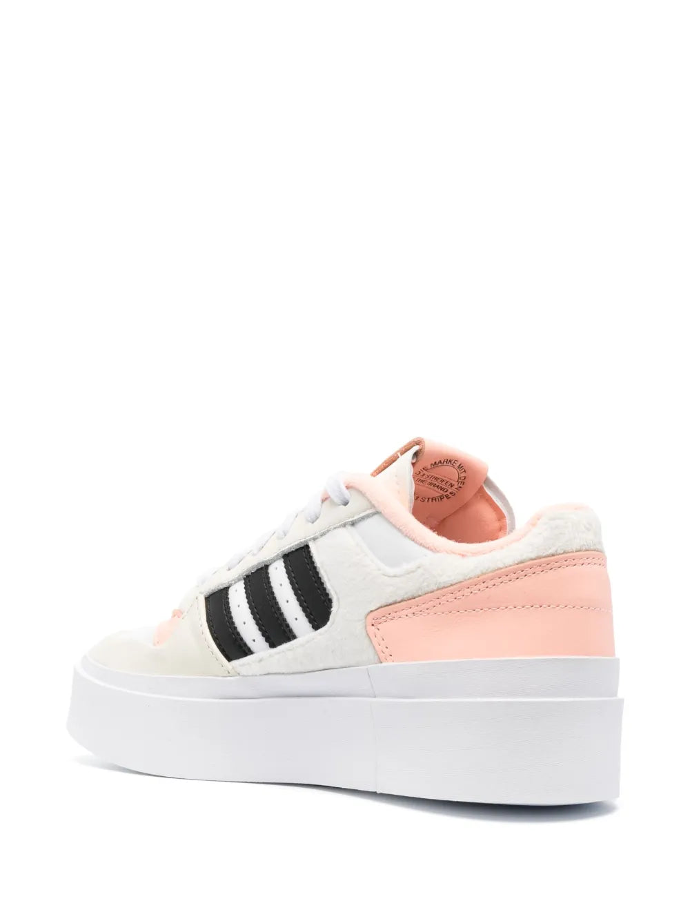 White low-top sneakers with black adidas stripes and pink heel panel.