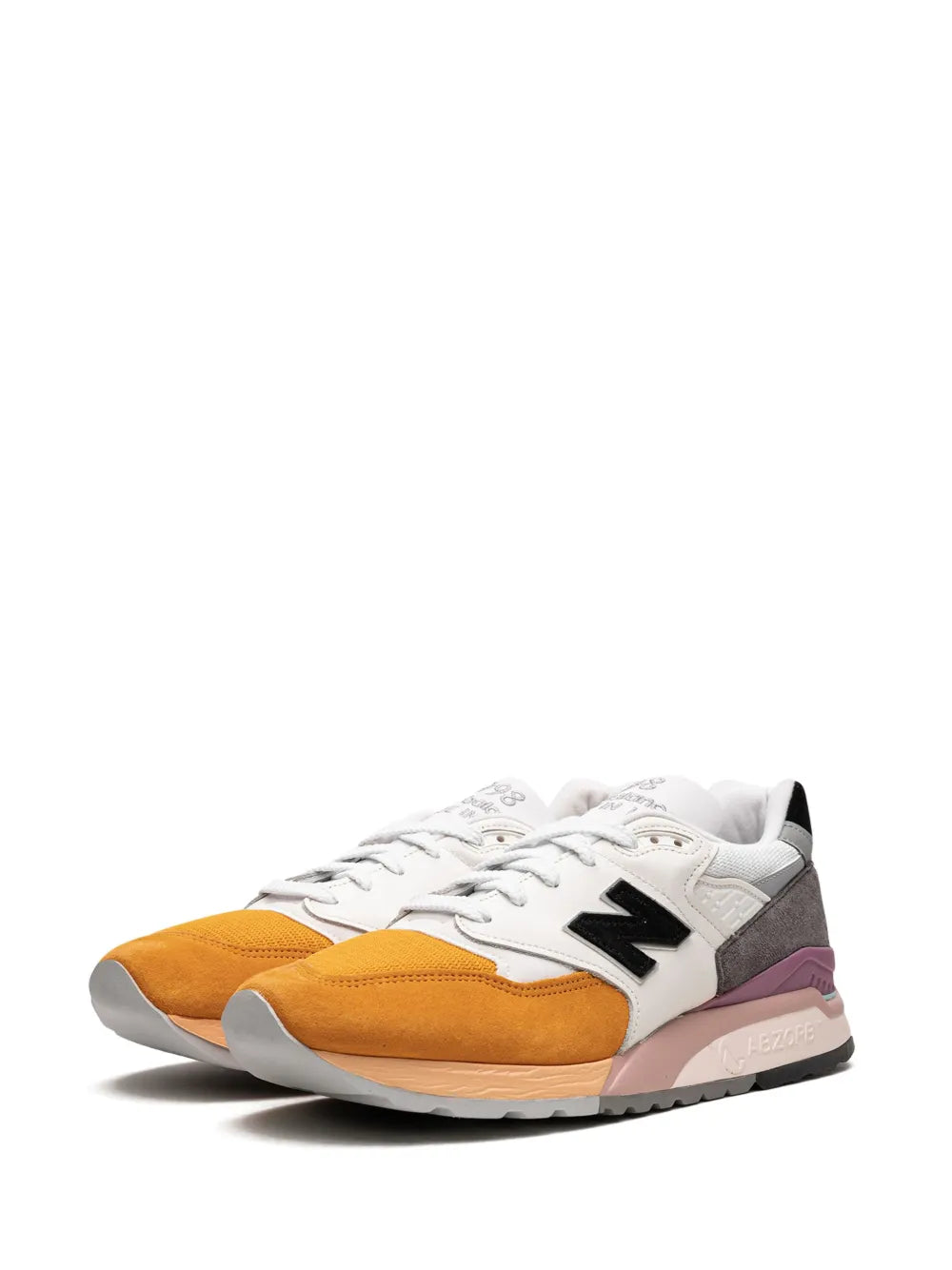 Sneakers angled view: white laces, black N logo, gray panels, orange toe, purple midsole