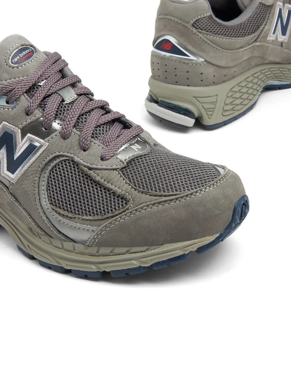 Ash grey New Balance 2002R sneakers, close-up of laces, N logo, textured sole