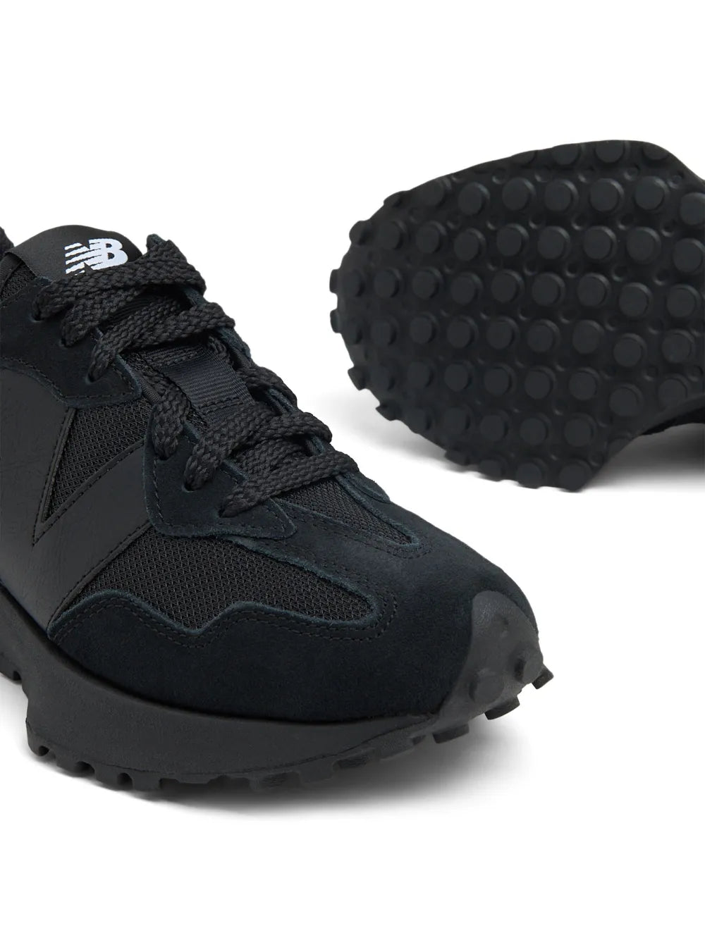 Black low-top sneakers, close-up: lace, mesh panels, and treaded rubber outsole
