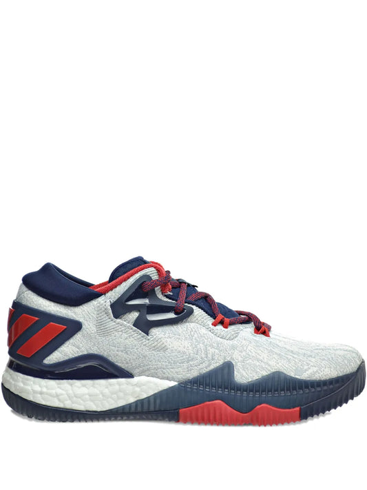 Grey low-top basketball shoe with navy heel, red laces and orange accents
