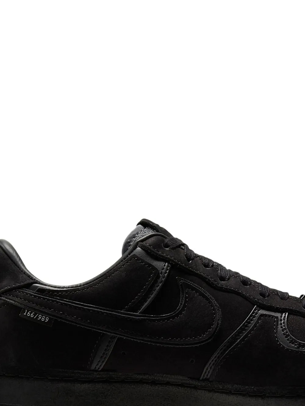 Black Nike low-top sneakers side view, lace-up with swoosh and textured toe