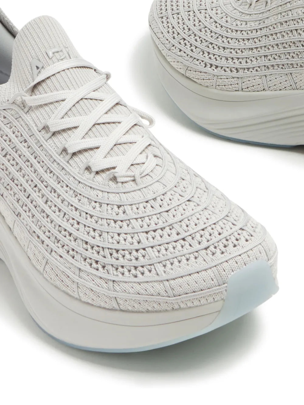 Light grey knit sneaker toe and laces close-up with blue-tinted sole edge