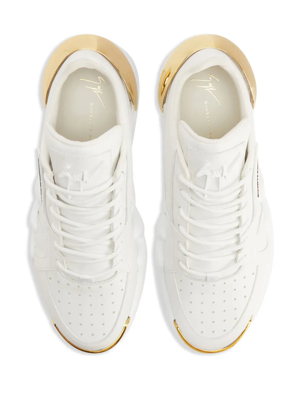White low-top sneakers close-up: lace-up front, perforations, gold collar trim