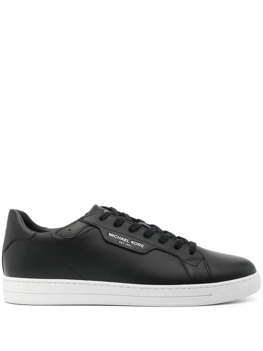 Black leather low-top sneaker with lace-up closure and Michael Kors logo