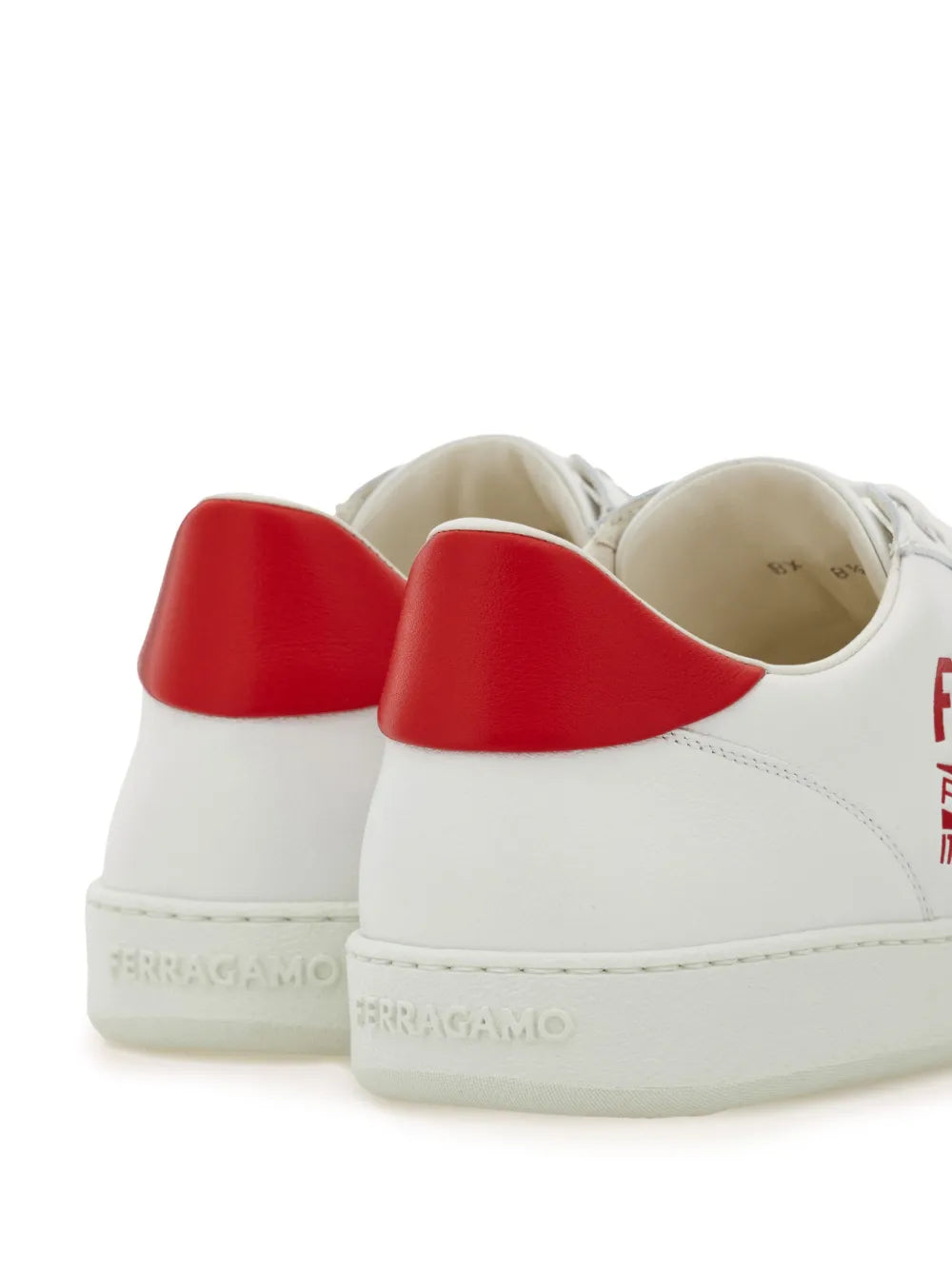 White leather sneakers with red heel lining and Ferragamo logo on heel