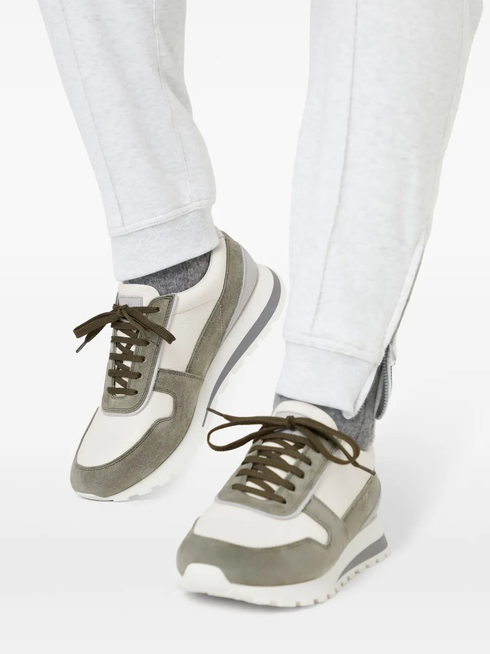 Lace-up trainers in white and olive green worn with light trousers and chunky sole