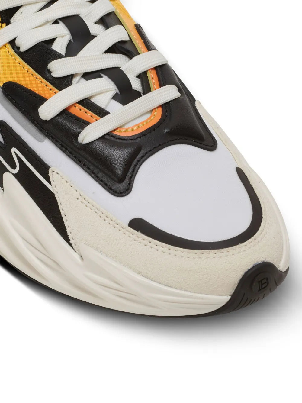 Close-up of white and black trainers with orange trim, lace-up eyelets, and panel stitching