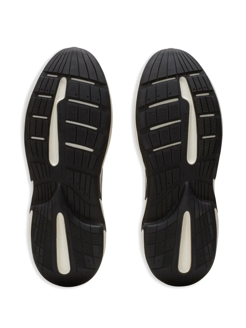 Black rubber outsole view of trainers with textured tread and white midsole sections