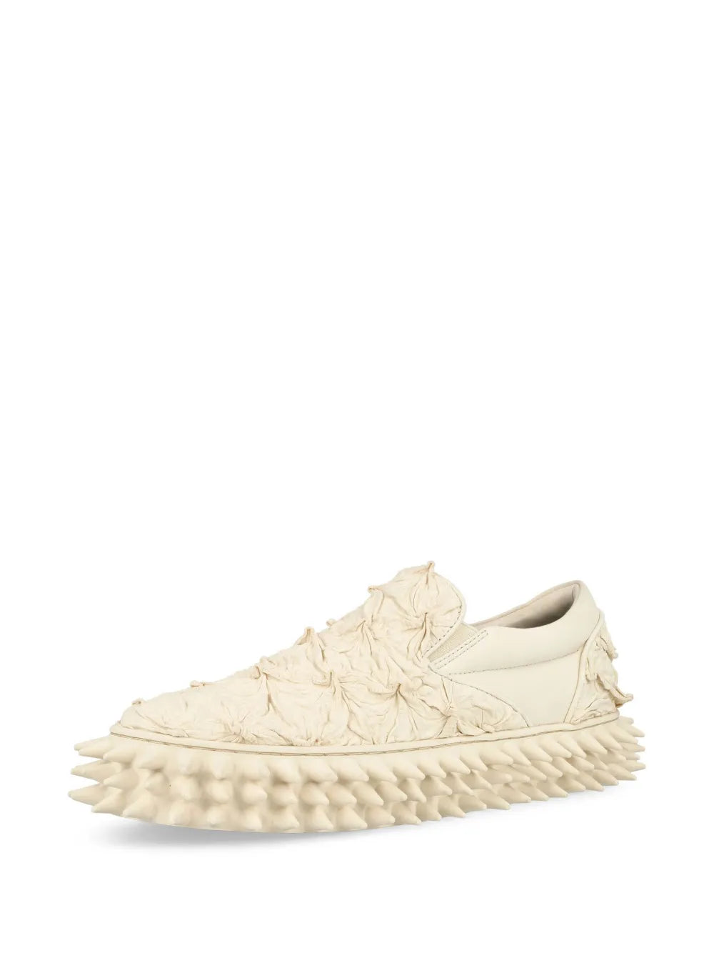 Ivory slip-on sneakers, side view, with ruched texture and spiked outsole