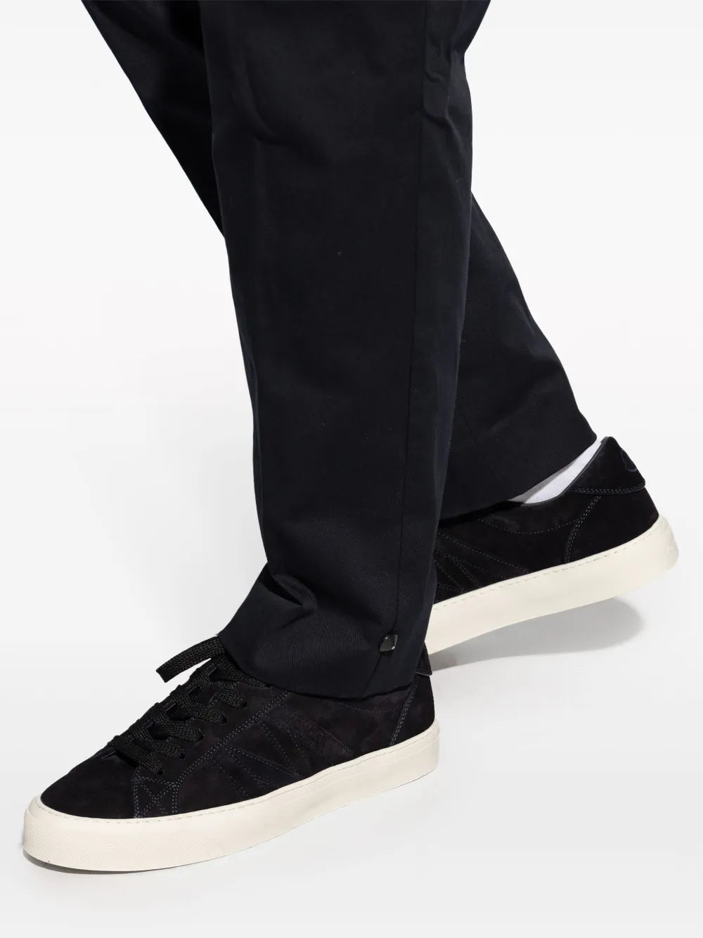 Black sneakers and white sole shown with dark trousers